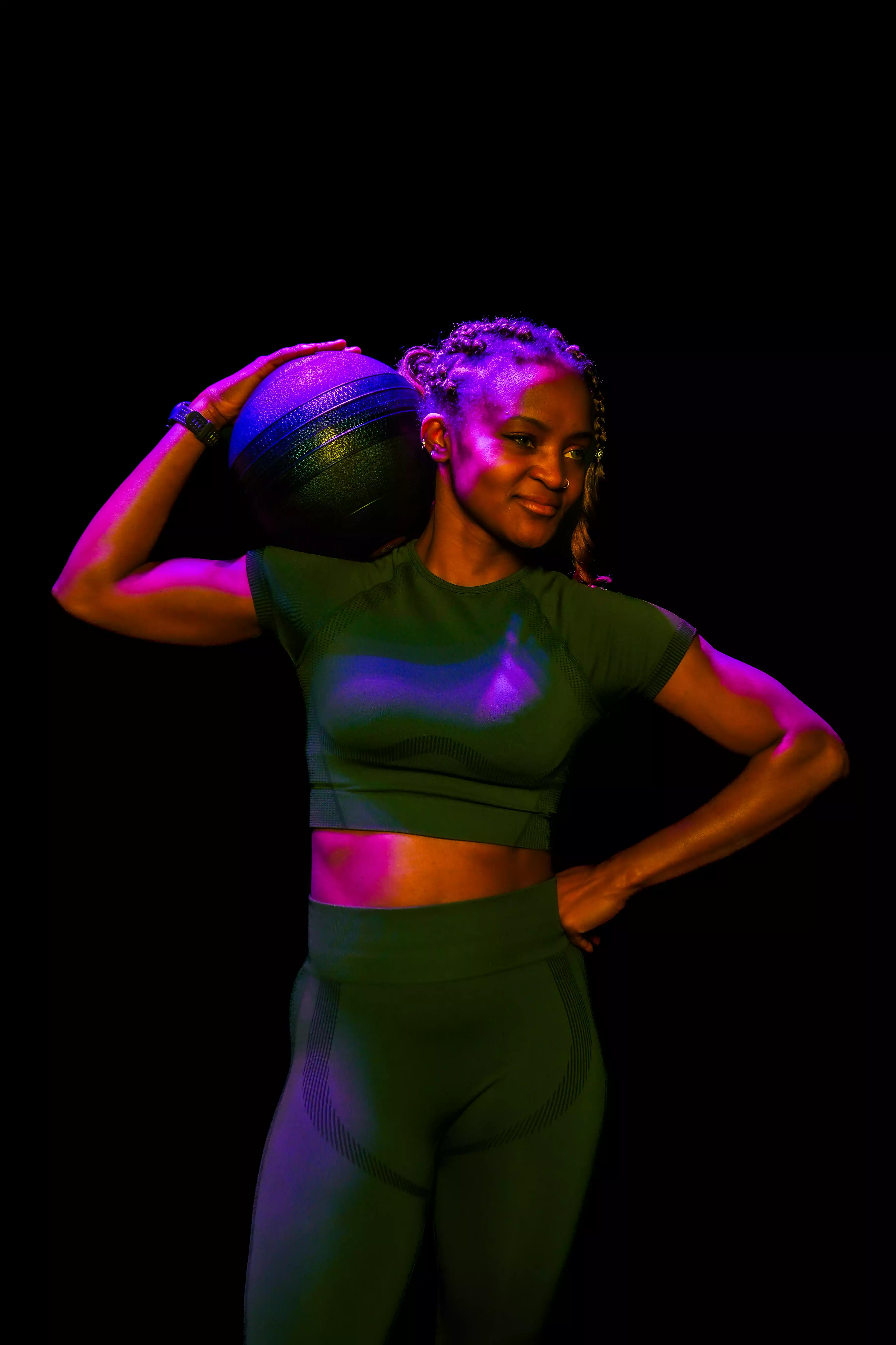 Femme en tenue sportive tenant boule de médicine, salle de sport moderne, entraînement musculation.